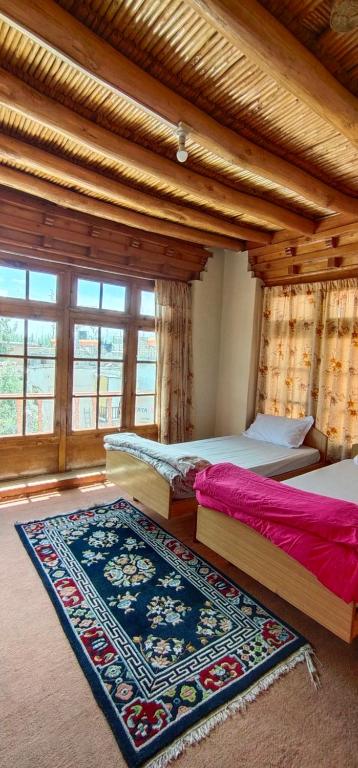 a bedroom with two beds and a rug at Thangkop House in Leh