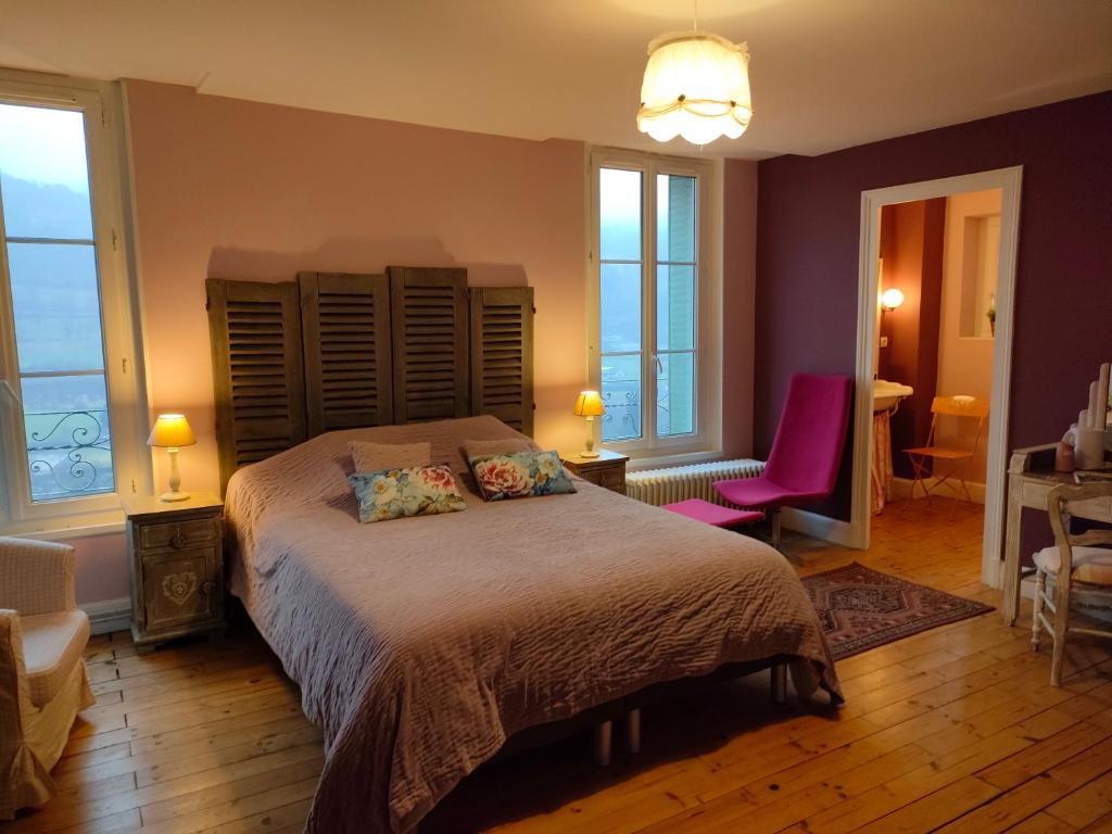 a bedroom with a large bed with purple walls and windows at La Maison de Jeanne, maison d'hôtes in Thiézac