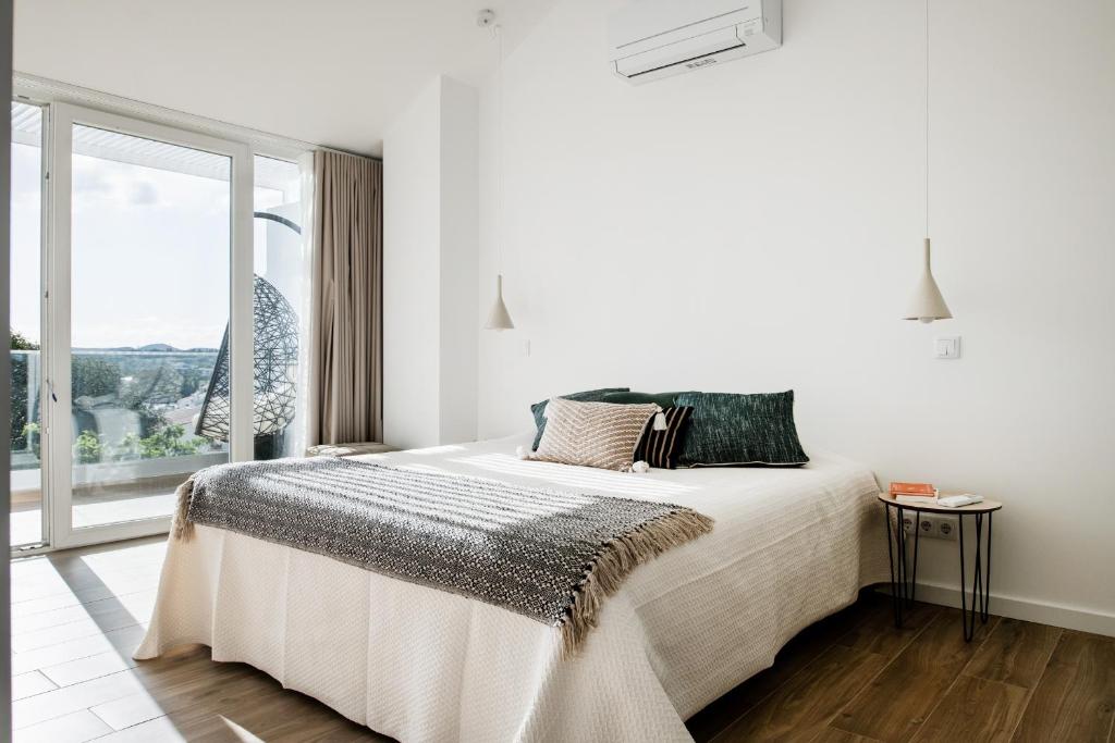 a white bedroom with a bed and a large window at Casa Nova in Silves