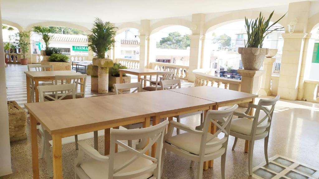 a dining room with tables and white chairs at Hotel Nou Can Guillem in Cala Figuera