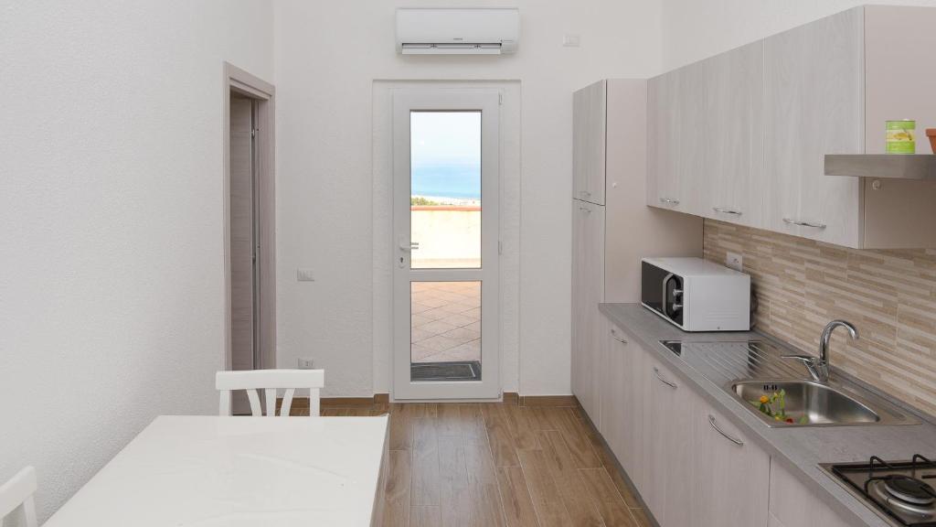 une cuisine blanche avec un évier et une fenêtre dans l'établissement Welcomely - Villa Paola B, à Costa Rei