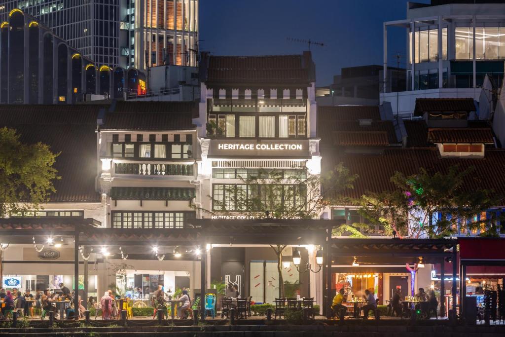 um grupo de pessoas sentadas fora de um edifício à noite em Heritage Collection on Boat Quay - Quayside Wing - A Digital Hotel em Singapura