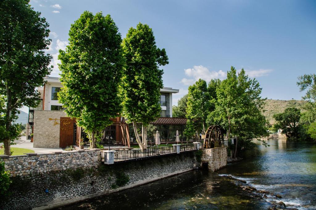 un bâtiment à côté d'une rivière arborée dans l'établissement Hotel Buna Mostar, à Buna