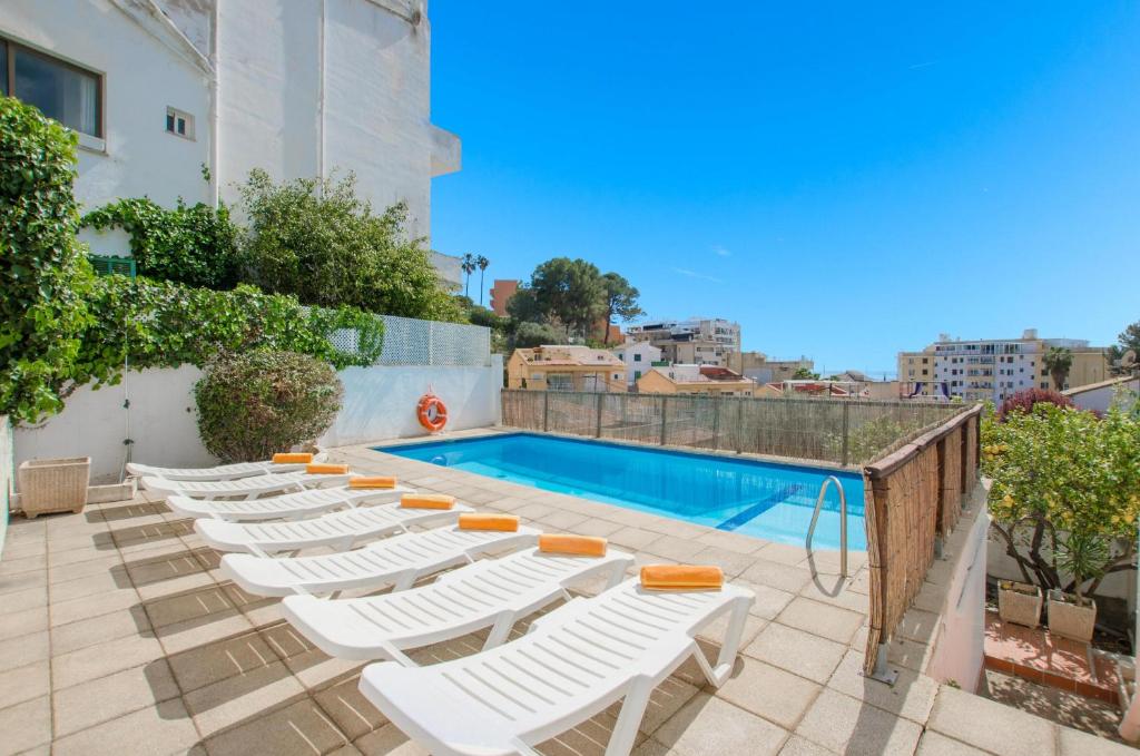 a row of white lounge chairs next to a swimming pool at YourHouse Ca Na Salera, villa near Palma with private pool in a quiet neighbourhood in Palma de Mallorca