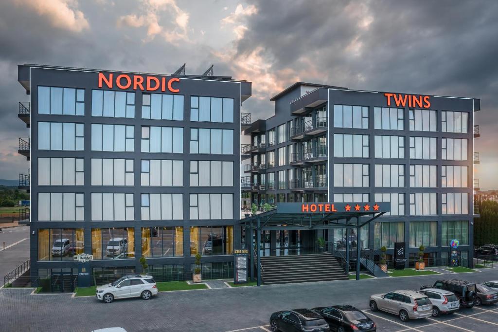 ein Hotel mit Autos auf einem Parkplatz in der Unterkunft Hotel Nordic Twins in Rădăuţi