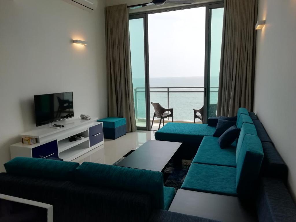 uma sala de estar com sofás azuis e uma televisão em Apartment Universal em Galle