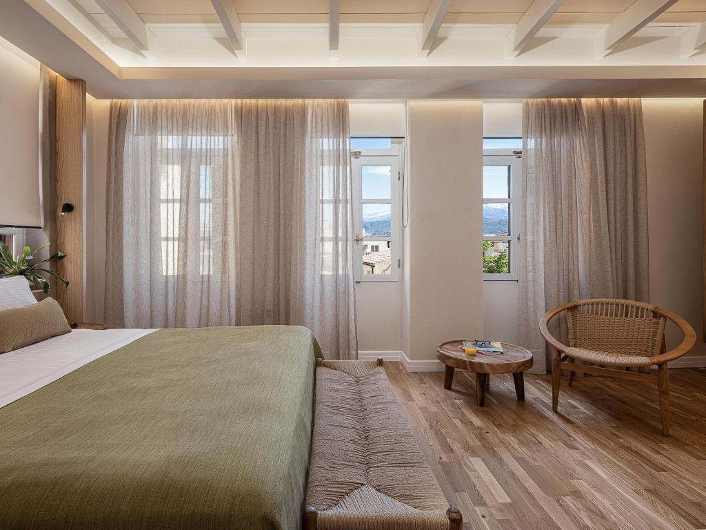 a bedroom with a bed and a chair and windows at Lithinon Luxury Suites with Free Parking in Chania Town