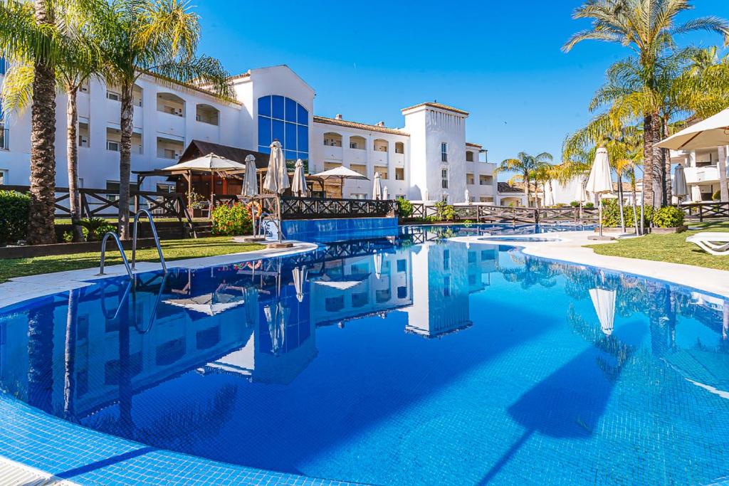 a pool at a resort with palm trees at Aparthotel Cordial Mijas Golf in Mijas