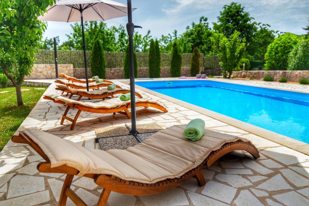 a patio with chairs and an umbrella next to a swimming pool at Villa Prima Natura, Imotski private pool in Imotski