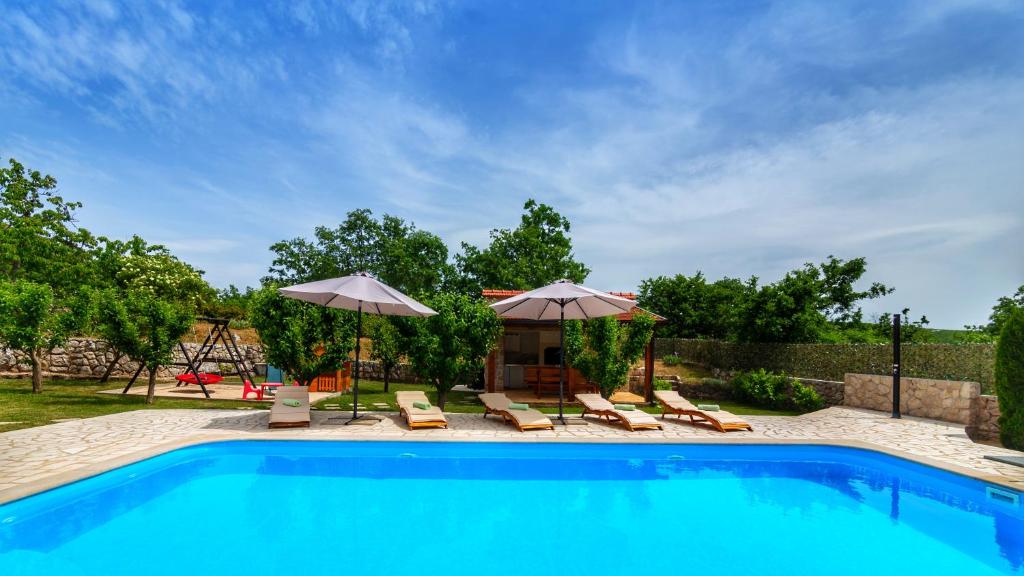 a swimming pool with chairs and umbrellas at Villa Prima Natura, Imotski private pool in Imotski
