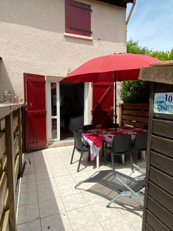 a table with a red umbrella on a patio at Charmante maison au coeur de la pinède Classée 3 étoiles in Lacanau