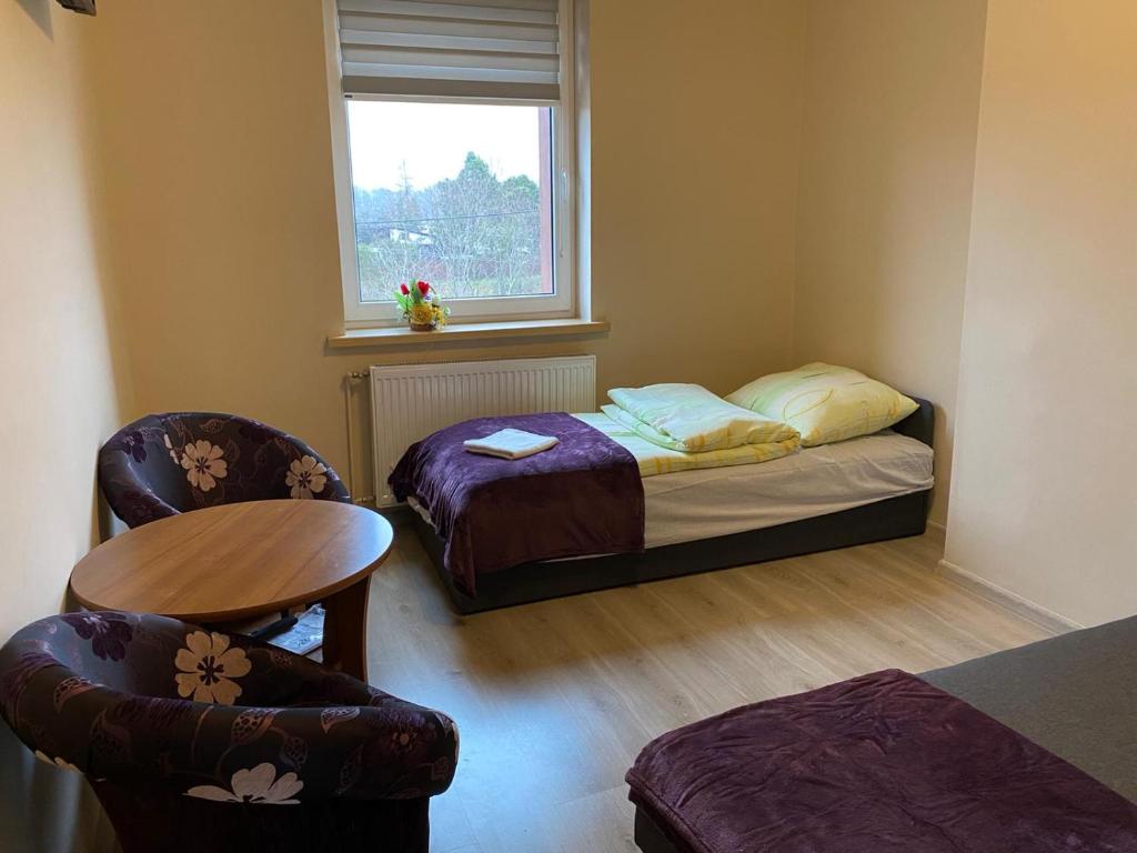 a small room with a bed and a table and chairs at Pod Lipami in Kołczygłowy