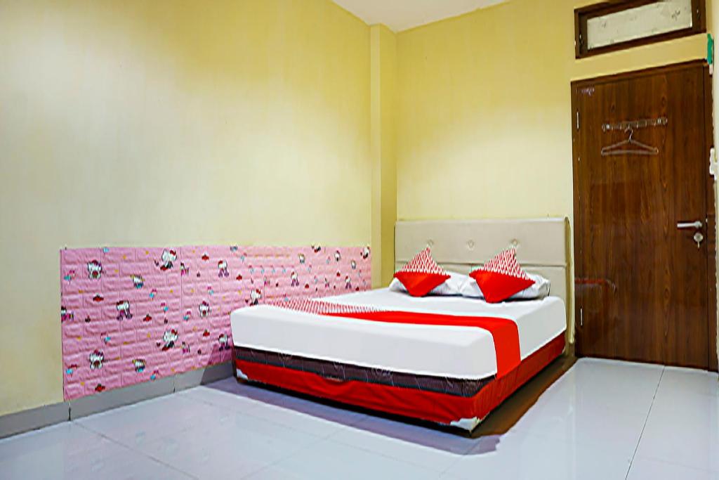 a bedroom with a large bed with red pillows at OYO 91182 Kos'ta Homestay Makassar in Makassar