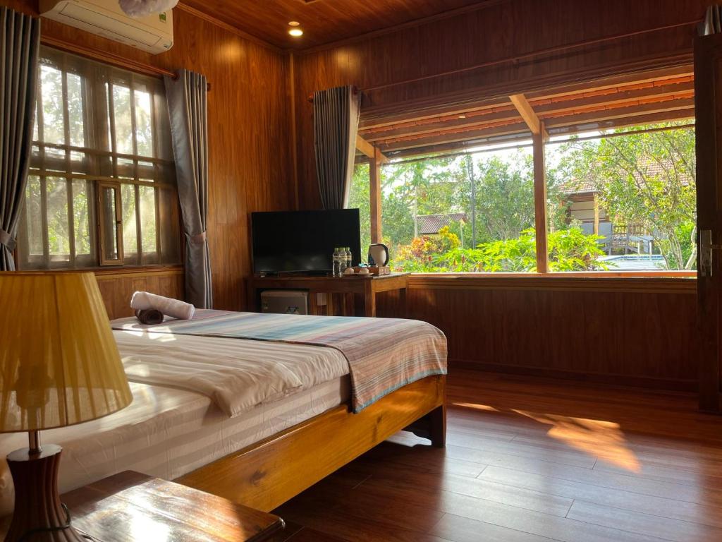 a bedroom with a bed and a large window at Phu Quoc Pomelo Garden in Phu Quoc