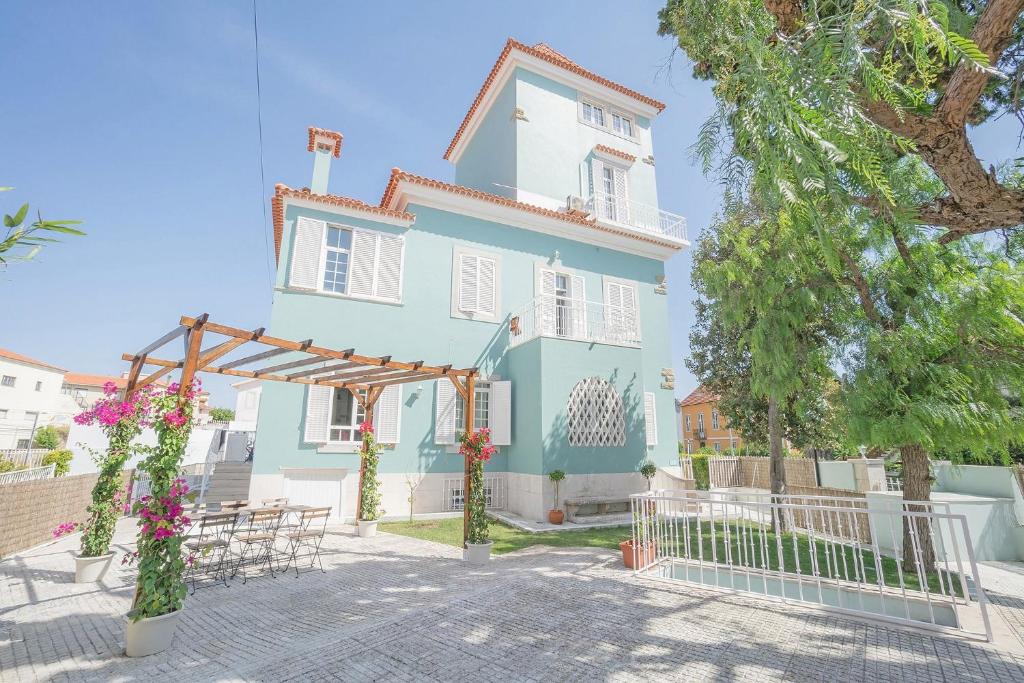 Casa azul y blanca con mesas y sillas en Impact Beach House, en Estoril