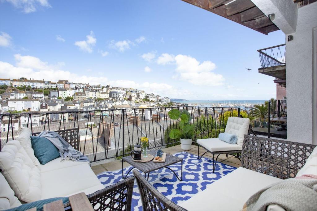 einen Balkon mit einem Sofa, einem Tisch und Stühlen in der Unterkunft Brixham Breeze in Brixham