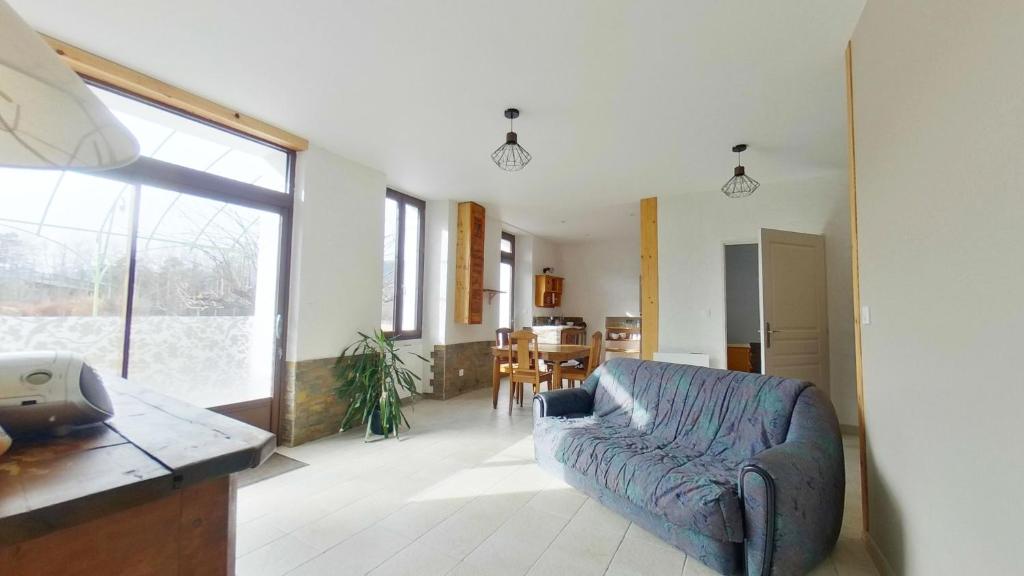 a living room with a blue couch and a kitchen at Appartement entier T4 à Jausiers in Jausiers