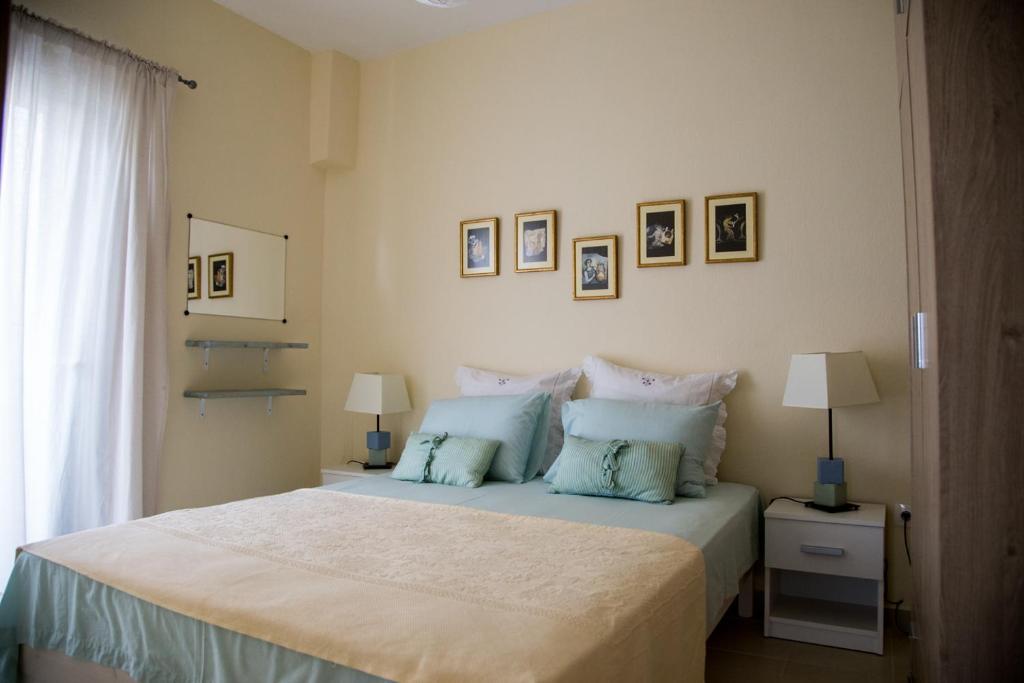 1 dormitorio con 1 cama grande con almohadas azules en Blue Theros Apartments, en Paralia Dionisiou