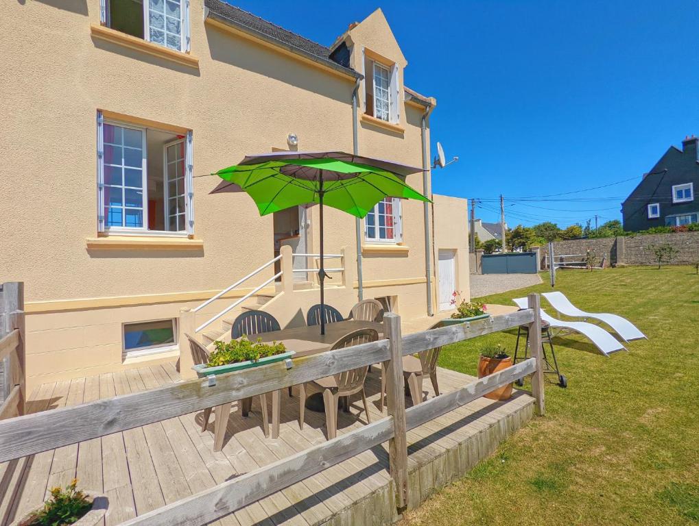 a patio with a green umbrella on a house at La Villa Ty Reun - Vue mer et Plage à 100m in Plouguerneau