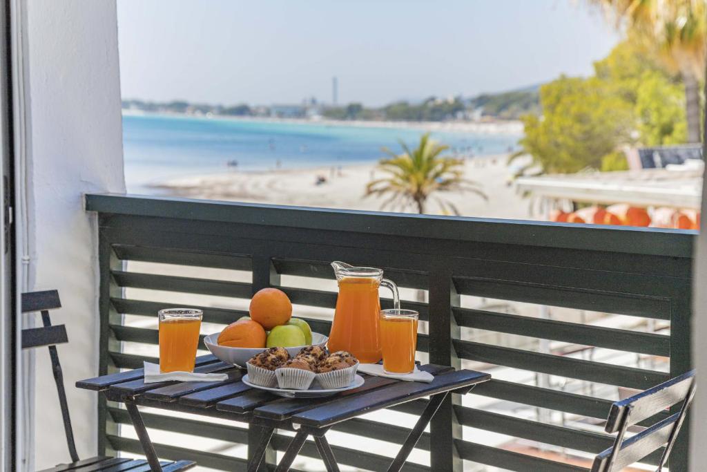 a table with fruit and juice on a balcony with a beach at Apartamento Xara in Alcudia