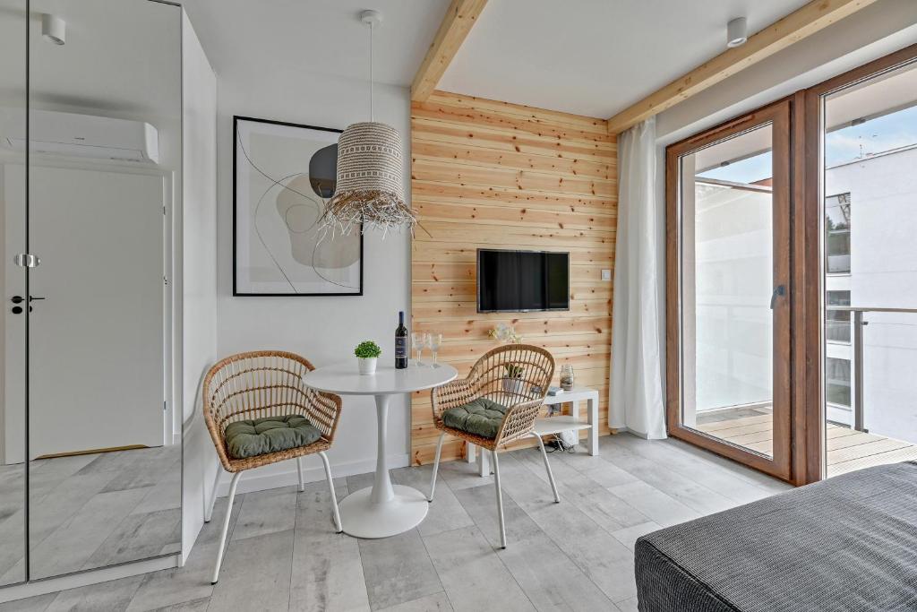 a room with a table and chairs and a tv at Apartamenty PIAMOLA Baltic Park Stegna in Stegna