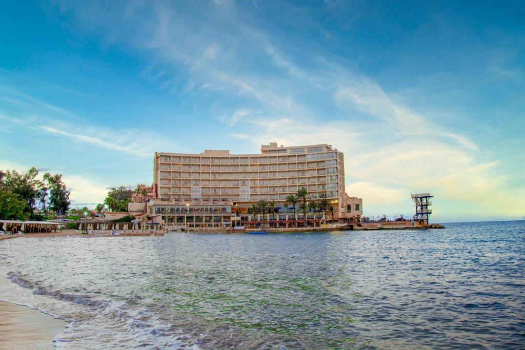 un gran hotel a orillas de un cuerpo de agua en Helnan Royal Hotel - Montazah Gardens, en Alejandría