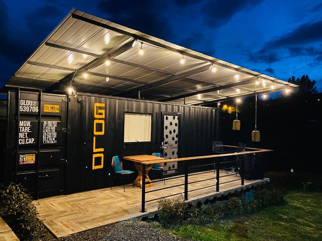 ein Gebäude mit einem Tisch auf einer Terrasse in der Nacht in der Unterkunft Acogedor y moderno Glamping en container, 10 min del centro in Chiquinquirá