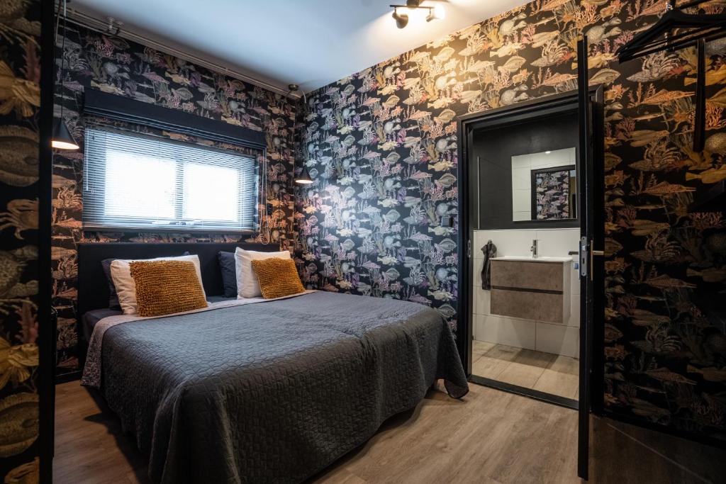 een slaapkamer met een bed in een kamer met behang bij Cosy Aquarium for a couple or friends in Groningen