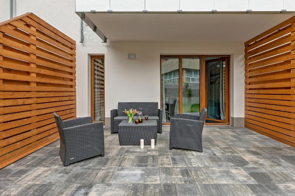 Outdoor patio with dark wicker sofa and chairs around coffee table, wooden privacy panels.