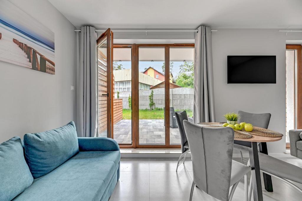 Bright living area with blue sofa, dining table and chairs, glass doors opening to backyard patio.