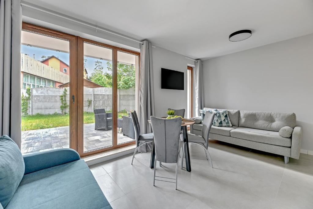 Living area with sliding glass doors opening to patio, dining table and sofa.