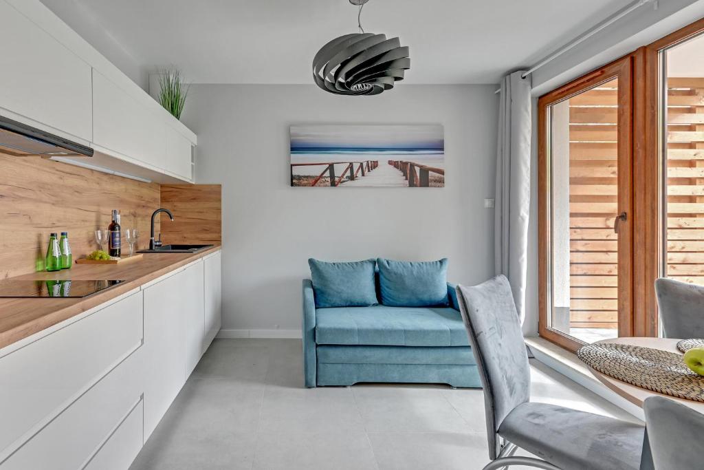 Compact kitchenette and seating area with blue sofa, wooden backsplash and patio doors.