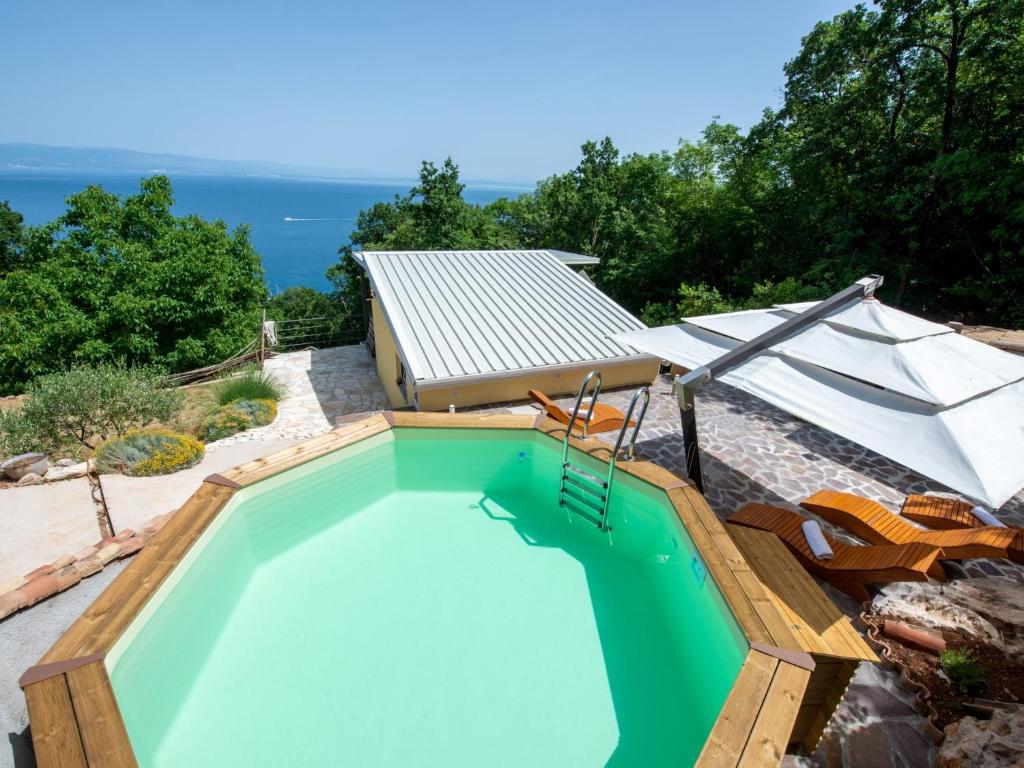 a swimming pool with chairs and an umbrella at Ferienhaus Baraka - Medveja in Lovran