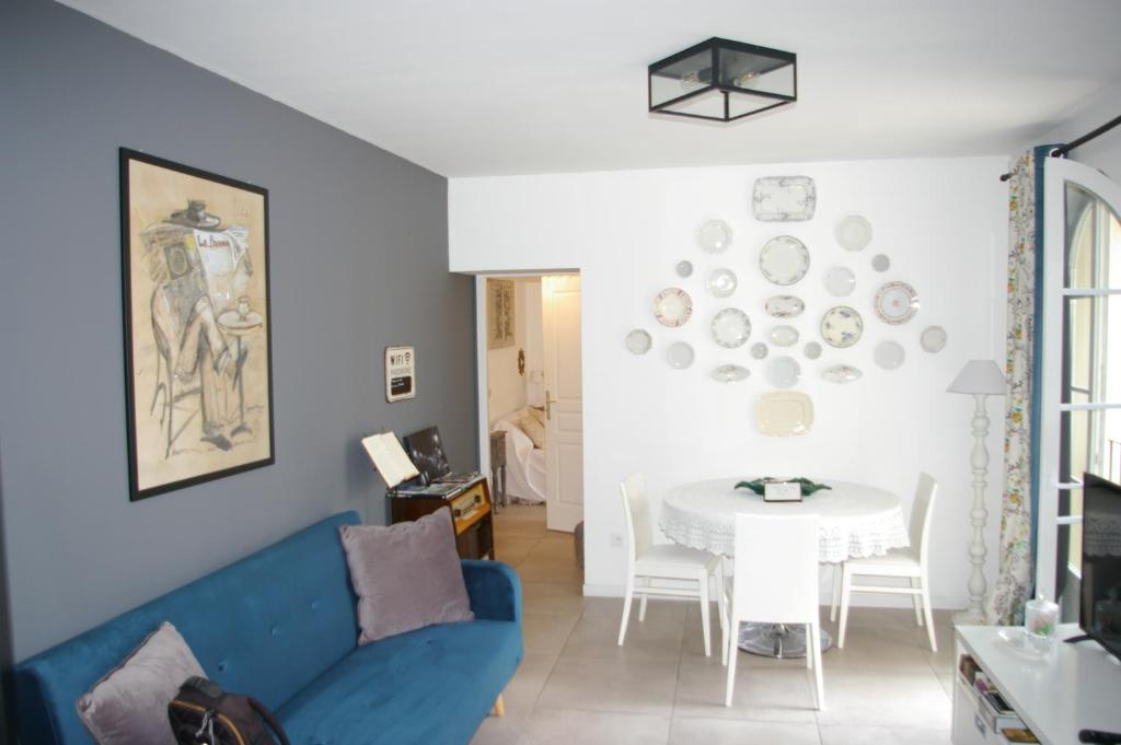 een woonkamer met een blauwe bank en een tafel bij Petit Rêve in LʼIsle-sur-la-Sorgue