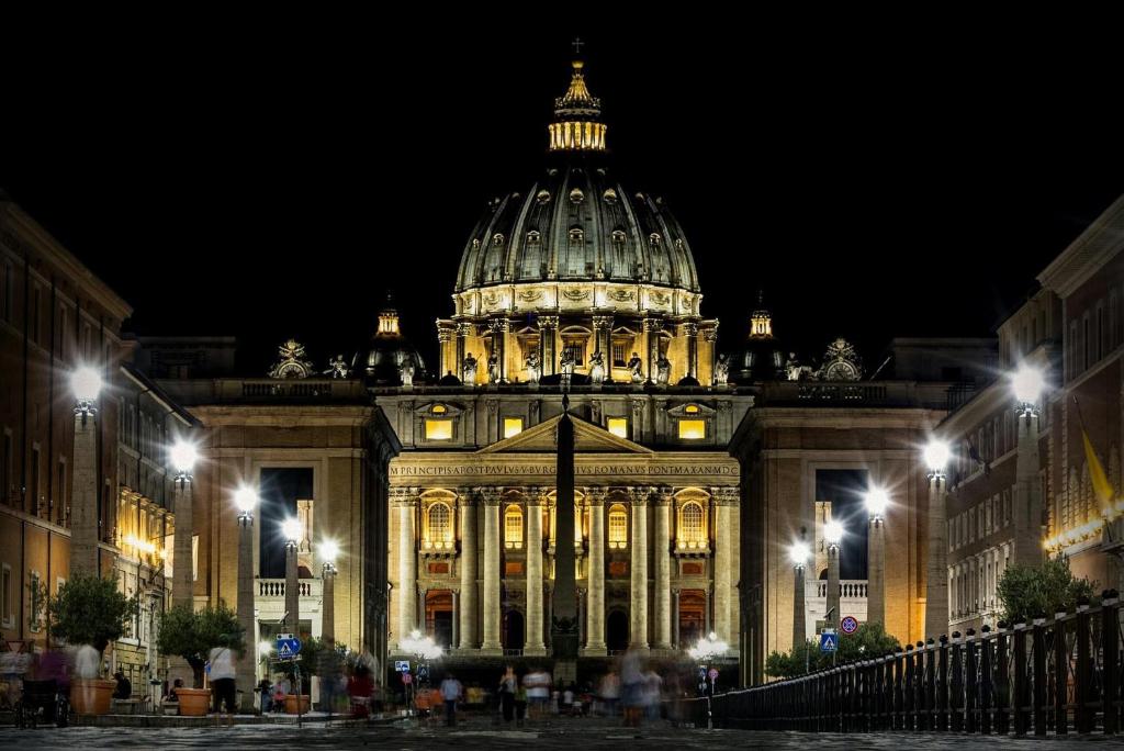 Ein nachts beleuchtetes Gebäude mit einer Kuppel in der Unterkunft Roma Vatican in Rom