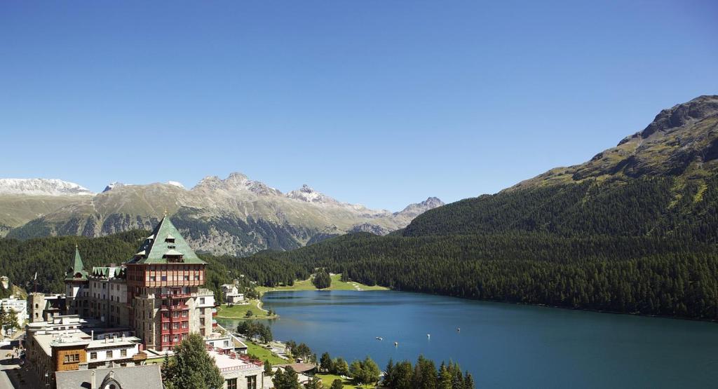 un grand bâtiment sur la rive d'un lac dans l'établissement Badrutt's Palace Hotel St Moritz, à Saint-Moritz