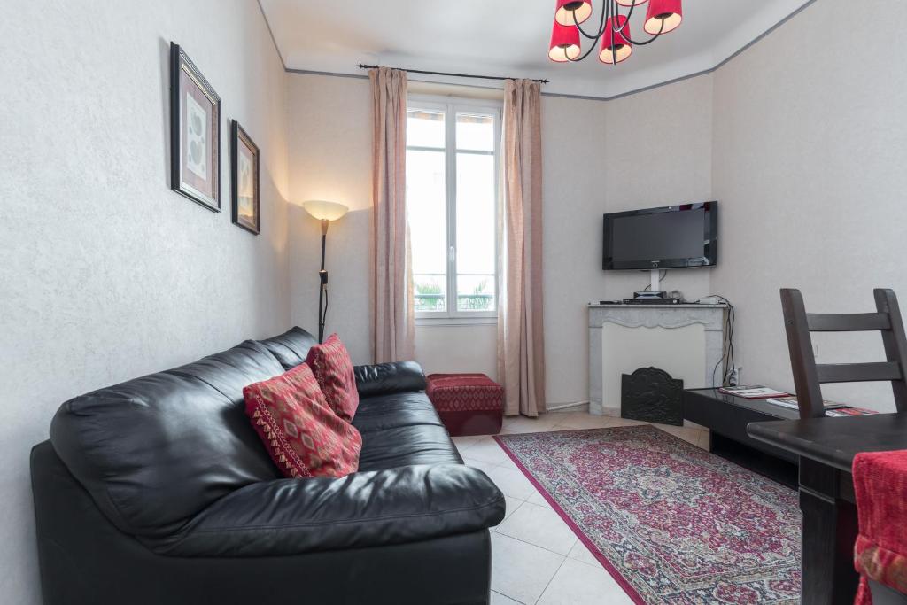 a living room with a black leather couch and a television at Three bedroom two bathroom apartment in center of Cannes on quiet street minutes from the Palais - 2002 in Cannes