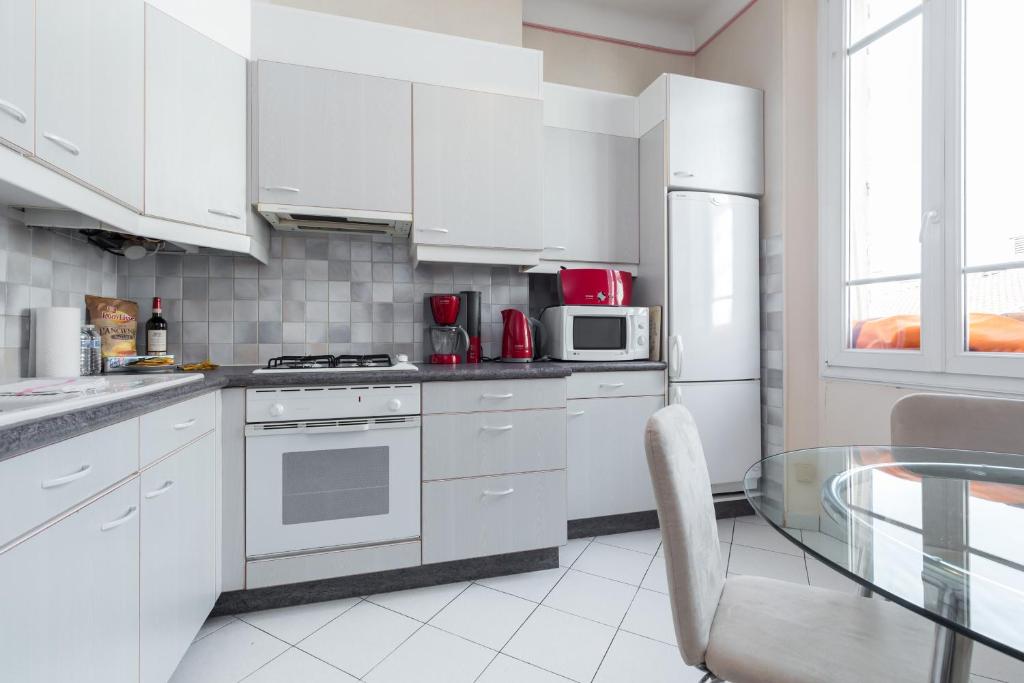 a kitchen with white cabinets and a glass table at Three bedroom two bathroom apartment in center of Cannes on quiet street minutes from the Palais - 2002 in Cannes
