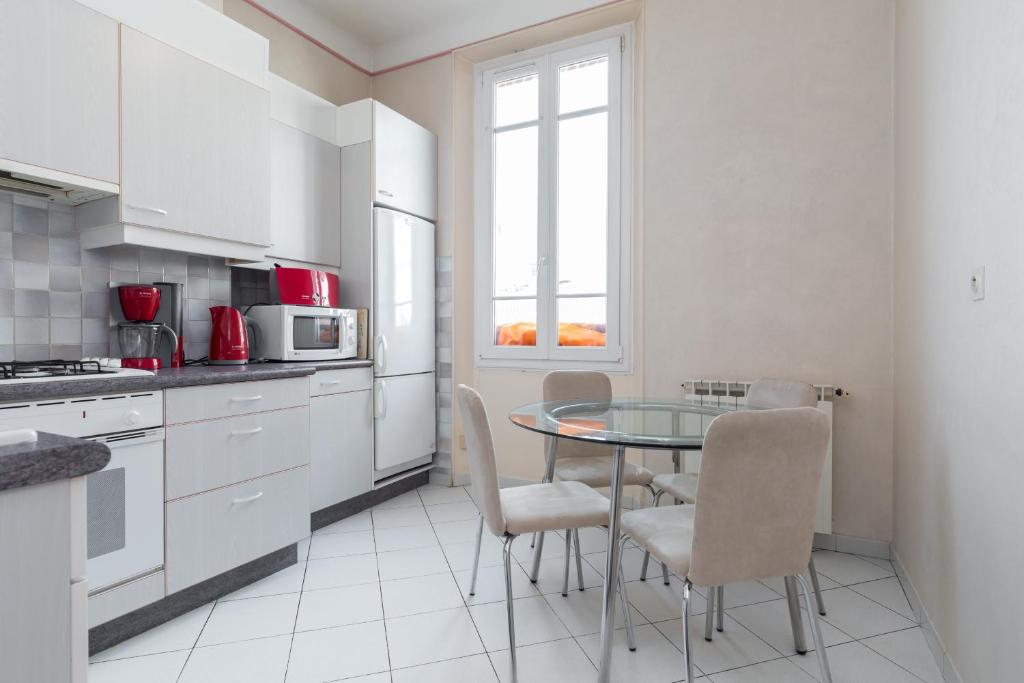 a white kitchen with a glass table and chairs at Three bedroom two bathroom apartment in center of Cannes on quiet street minutes from the Palais - 2002 in Cannes