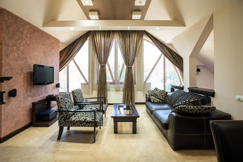 een woonkamer met een bank en stoelen en een tv bij Hotel Vila Lago in Palić