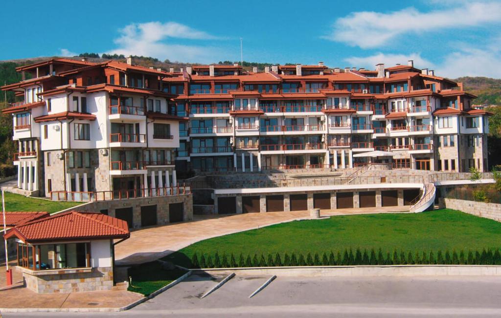 a large apartment building with a green lawn in front of it at Апартамент за гости Влади в комплекс Garden Palace Balchik in Balchik
