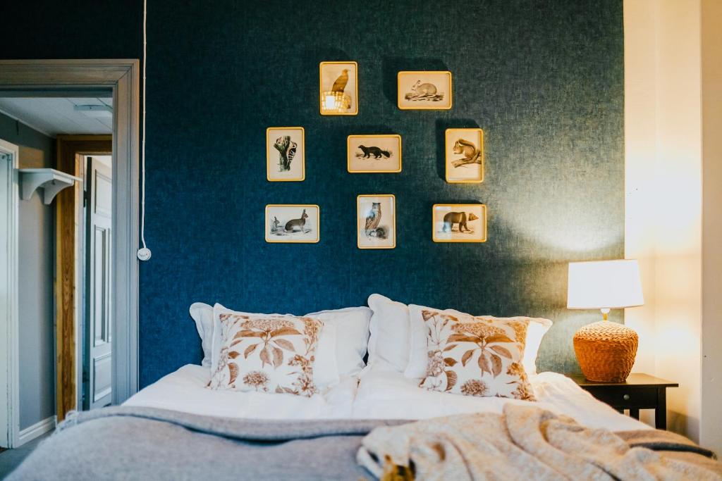 a bedroom with a bed and a blue wall with pictures at Salaisen Puutarhan Majatalo in Kauhajoki