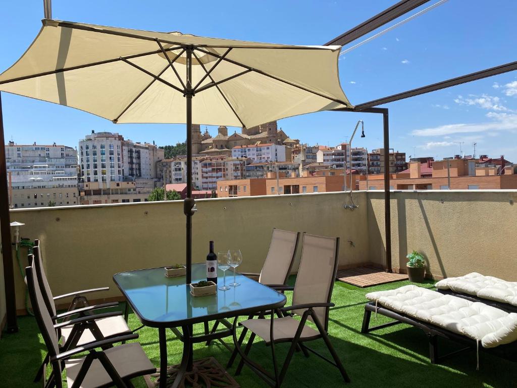 een tafel en stoelen met een parasol op een dak bij Apartamentos Alcañiz, Suite Deluxe in Alcañiz