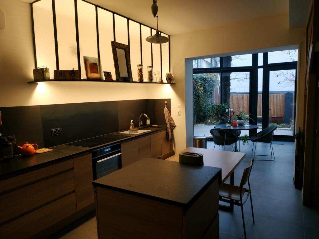 a kitchen with a counter and a dining room with a table at Le Palmier, Maison de ville, 3 chambres et jardin&#47;terrasse in Blois