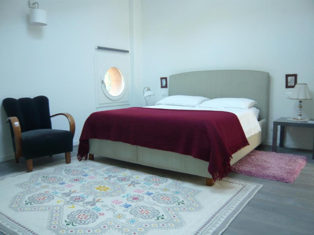 a bedroom with a bed and a chair and a rug at Villa Resta & Dependance in Castel San Pietro Terme