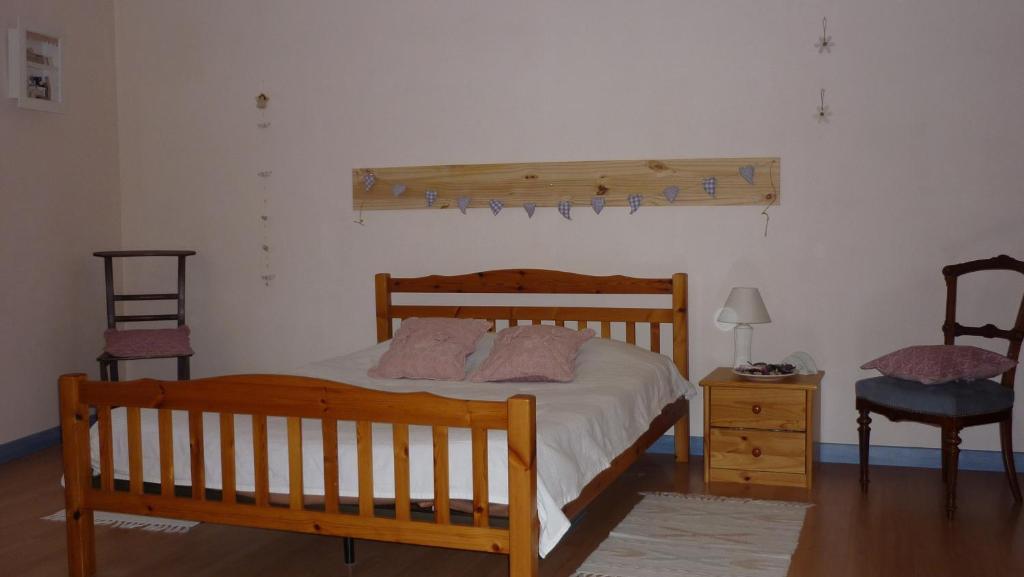 1 dormitorio con 1 cama de madera y 2 sillas en Meublé de tourisme Le Gilliard, en Chavanges