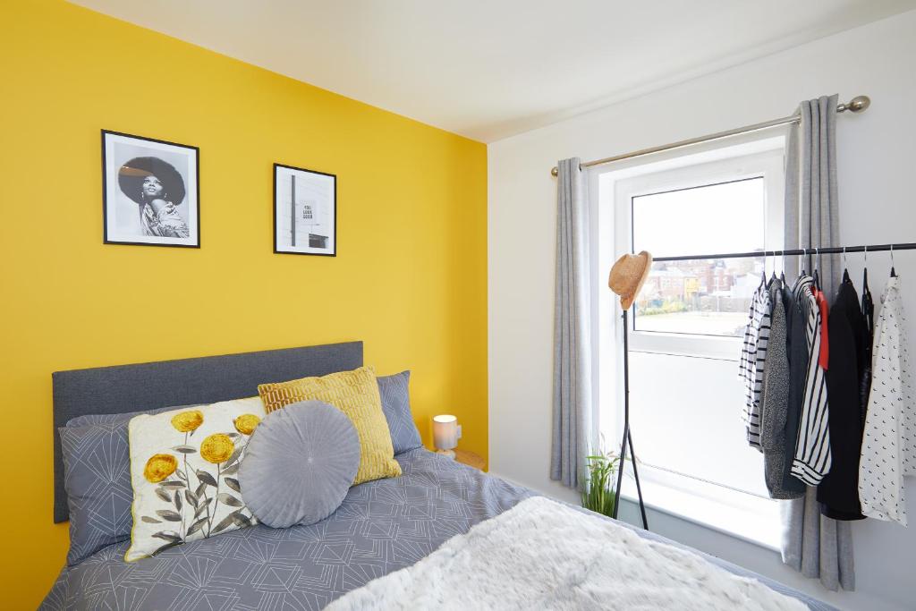 a bedroom with a bed and a yellow wall at Modern Derby Train Station Town House in Derby