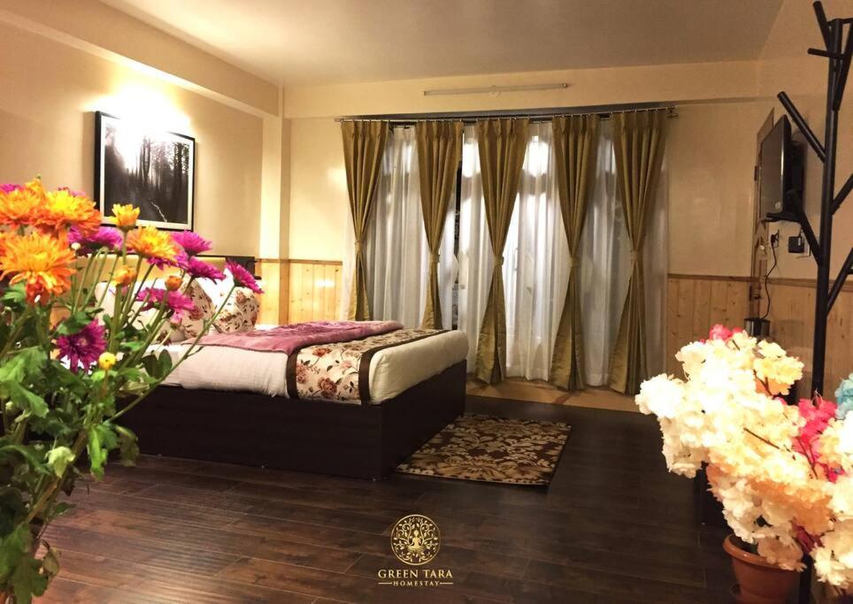 een slaapkamer met een bed en bloemen in een kamer bij Green Tara Homestay in Gangtok