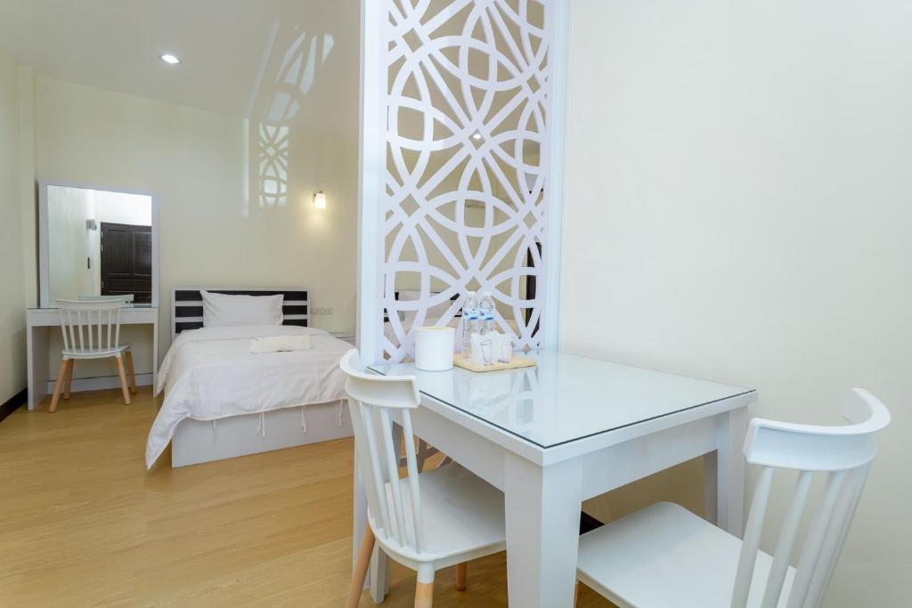 Cette chambre blanche comprend un bureau et un lit. dans l'établissement Thai Guest House, à Ban Don Klang