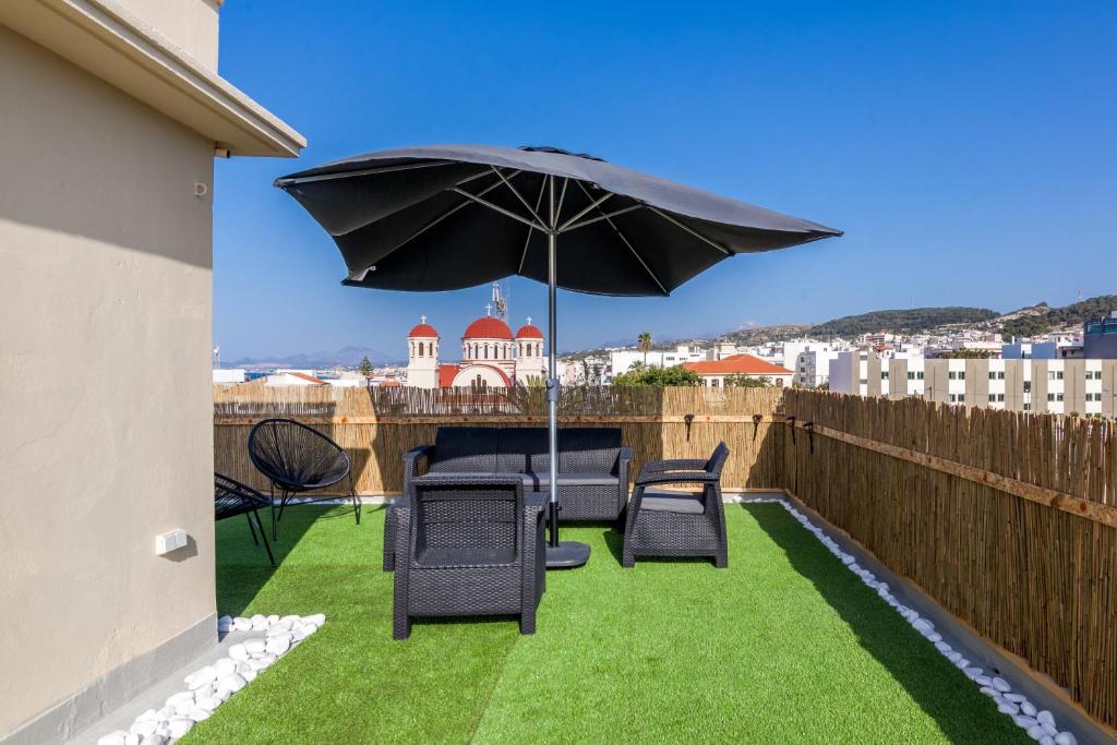 - une terrasse avec 2 chaises et un parasol dans l'établissement Renaissance Apartment, feeling the heartbeat of Rethymno!, à Réthymnon